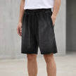 FJØRNA men's casual relaxed knit shorts in water-washed black with distressed finish and raw hem, showcasing comfort and style.