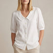 White women's summer blouse by FJØRNA with puff sleeves, linen fabric, and button front detail.