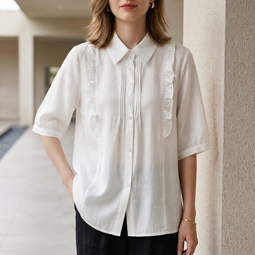White denim ruffle summer blouse for women by FJØRNA, featuring a stylish ruffled neckline and lightweight fabric.