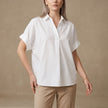 White FJØRNA summer women's blouse with short sleeves and denim fabric, featuring a loose fit and wide-leg style.