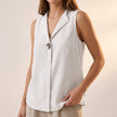 White sleeveless V-neck blouse for women by FJØRNA with statement button details, styled as a fashionable top.