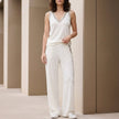White relaxed V-neck sleeveless lounge set with wide-leg pants, casual 2-piece FJØRNA lounge outfit on a model.
