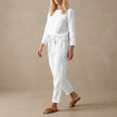 White linen two-piece set from FJØRNA featuring a boat neck blouse and drawstring pants, perfect for relaxed summer style.