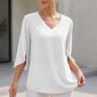White FJØRNA women's V-neck blouse with curved hem and slit sleeves, flowing and lightweight for a casual, elegant look.