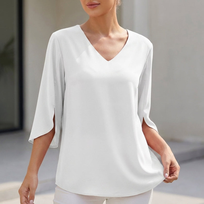 White FJØRNA women's V-neck blouse with curved hem and slit sleeves, flowing and lightweight for a casual, elegant look.