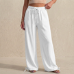 White linen women's summer trousers with drawstring waist and pockets, by FJØRNA, laid flat showing relaxed fit and lightweight fabric.