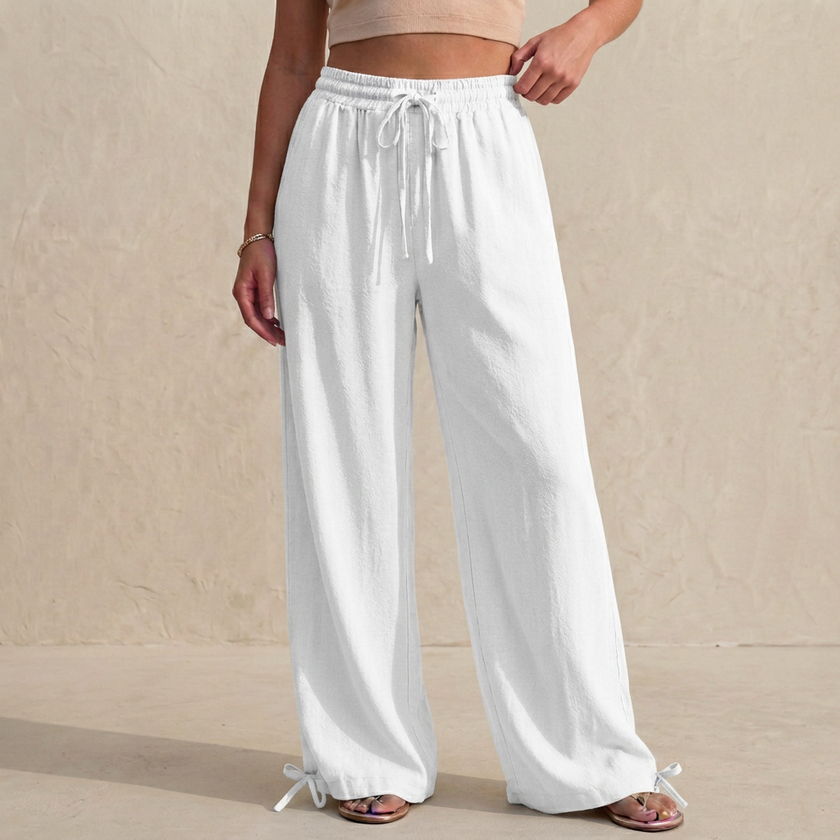 White linen women's summer trousers with drawstring waist and pockets, by FJØRNA, laid flat showing relaxed fit and lightweight fabric.