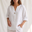 White women's summer blouse by FJØRNA featuring a V-neck, linen fabric, and button-front design.