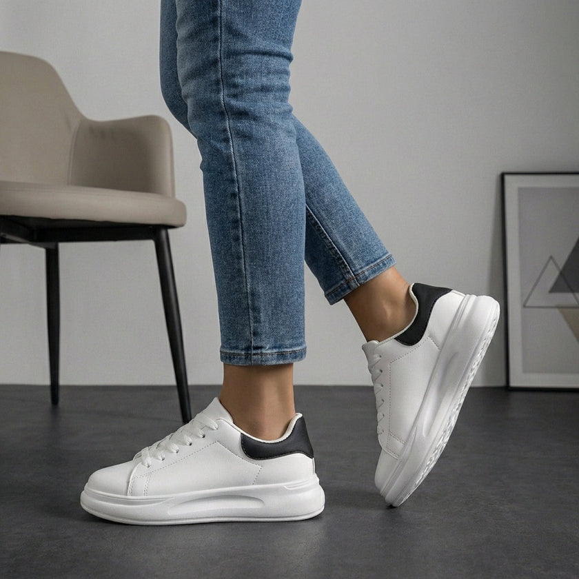 White and black FJØRNA women's orthopedic sneakers with lace-up design and arch support.