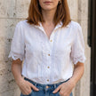 White FJØRNA summer women's blouse with V-neck, short sleeves, and lace detail, perfect for warm-weather outfits.