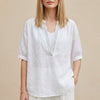 White women's summer blouse with V-neck and puff sleeves, by FJØRNA, shown on a model with a relaxed fit and lightweight fabric.