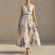 FJØRNA white pleated A-line maxi dress with V-neck and balloon sleeves, flowing fabric and elegant design.