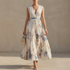 FJØRNA white pleated A-line maxi dress with V-neck and balloon sleeves, flowing fabric and elegant design.