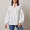 White FJØRNA summer blouse for women with V-neck, puff sleeves, and ruffle details, styled as a fashionable top.