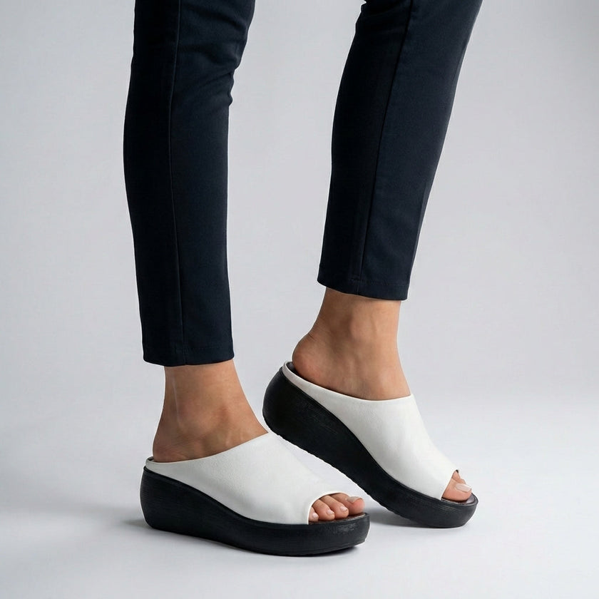 White FJØRNA orthopedic platform slide sandals with open toe and slip-on design, featuring cushioned footbed and chunky sole.