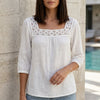 White FJØRNA summer blouse for women with a square neck and lace detail, perfect for warm weather and casual outings.