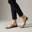 White FJØRNA ankle-length flat sandals with ankle strap and buckle, showcasing their minimalist design and comfortable fit.