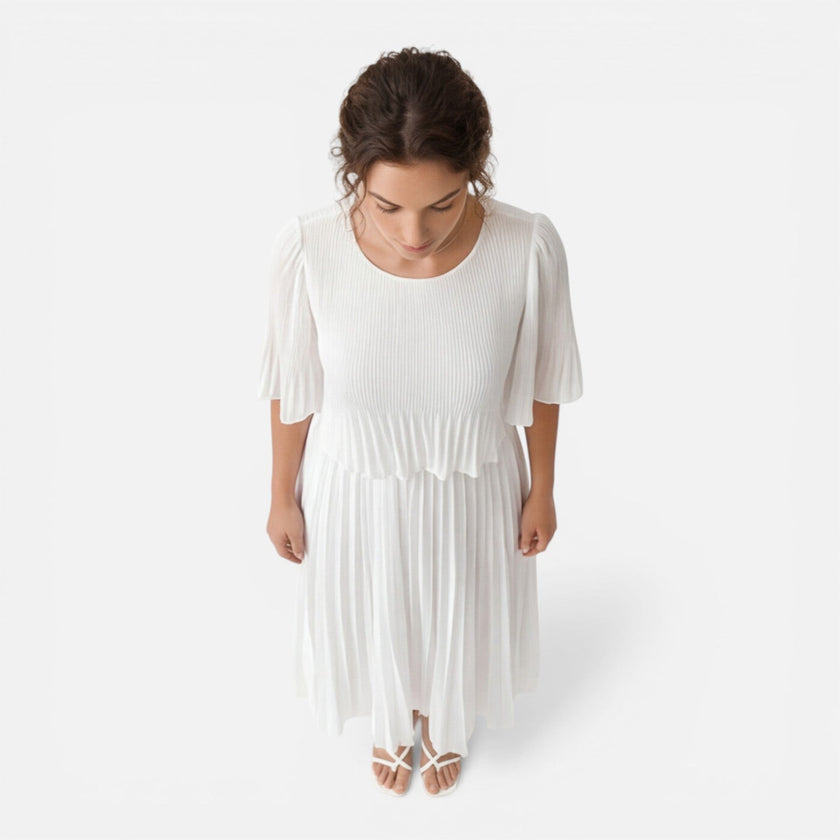 Women's white chiffon pleated maxi dress by FJØRNA, flowing fabric with a fitted waist and elegant pleats, perfect for wedding guests.