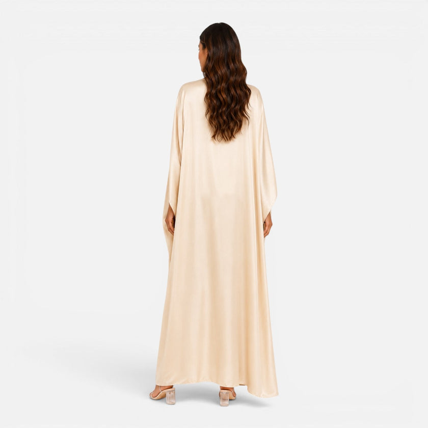 Woman wearing a FJØRNA women's draped sleeve maxi dress, flowing fabric, elegant design, full-length dress with draped sleeves.