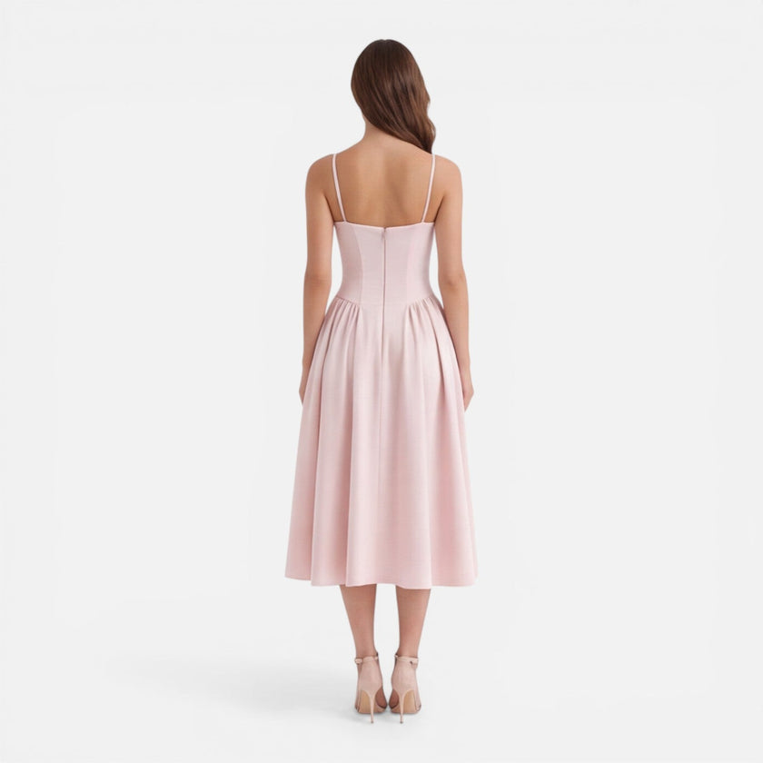 Elegant women's midi dress by FJØRNA with strap details, A-line silhouette, perfect for wedding guests, shown on a model.