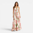Woman wearing a floral halter maxi dress by FJØRNA, showcasing a flowing, elegant design with vibrant floral patterns.