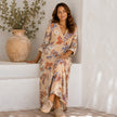 Women's boho floral print V-neck maxi dress by FJØRNA, flowing fabric with vibrant floral pattern and V-neckline.