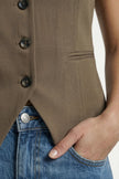 Close-up of FJØRNA women's slim fit sleeveless tailored waistcoat with layered design, showcasing fine fabric and precise stitching.