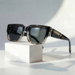Women's square sunglasses by FJØRNA with thick frames and wide temples, featuring dark tinted lenses and stylish design.