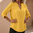 Yellow women's relaxed V-neck blouse with band collar and patch pocket, by FJØRNA, shown on a model.