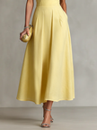 Yellow linen evening dress by FJØRNA, flowing fabric, sleeveless design, and elegant silhouette perfect for special occasions.
