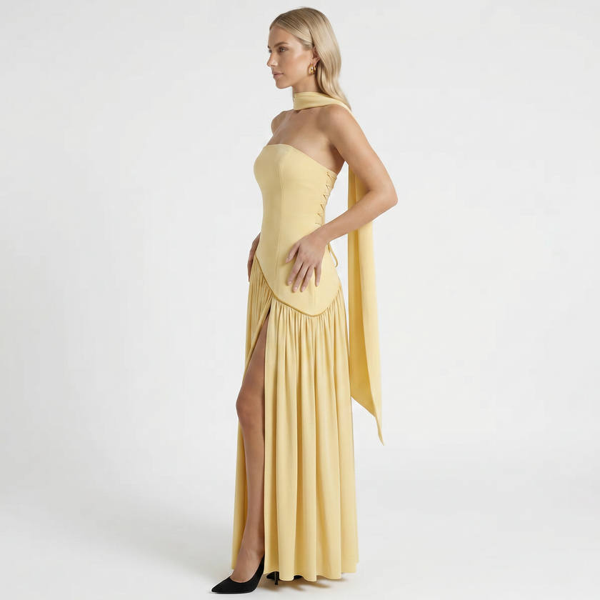 Yellow women's strapless maxi dress by FJØRNA shown from side profile, featuring a flowing silhouette and elegant design.