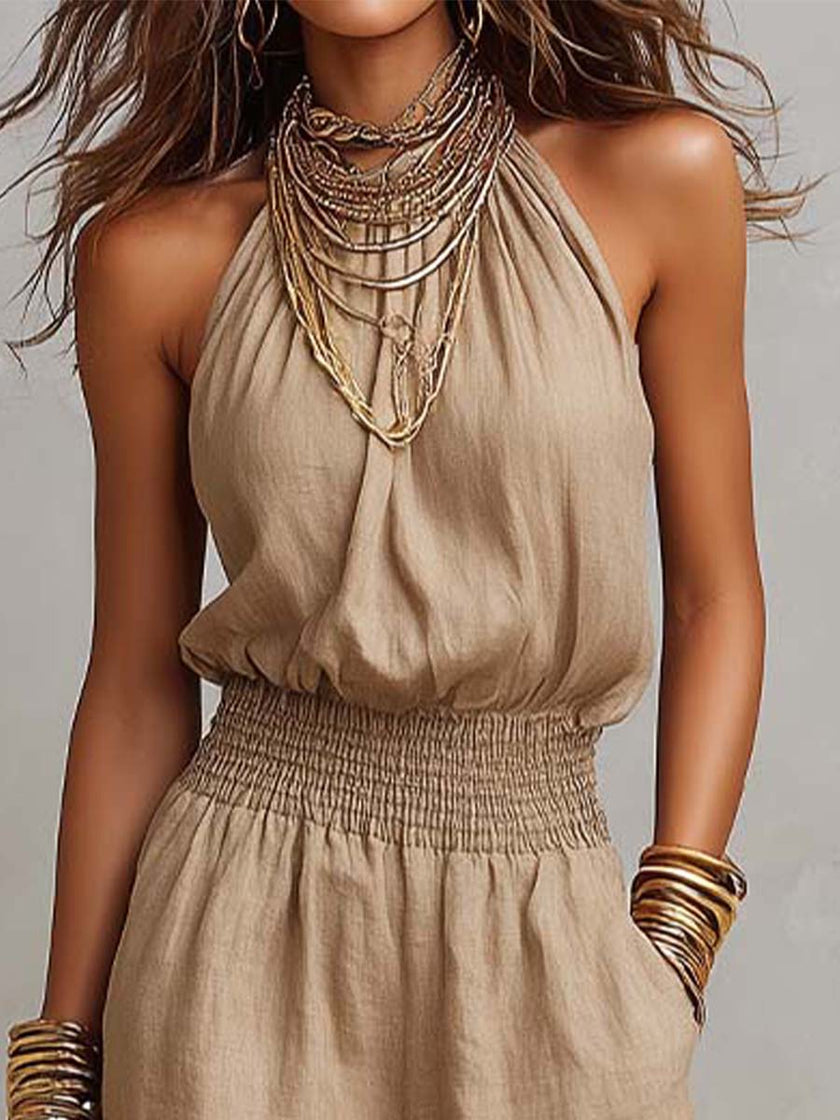 FJØRNA tan cotton linen sleeveless jumpsuit with halter neck, smocked waist, and wide-leg design, perfect for warm weather.