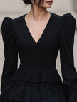 FJØRNA black leather mini dress with dramatic puff sleeves and tiered design, perfect for stylish, bold fashion statements.