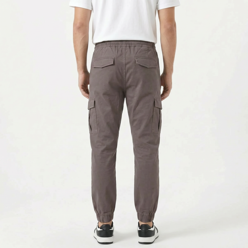 Men's slim fit cotton cargo trousers by FJØRNA, featuring multiple pockets and a modern fit, shown in a neutral color.
