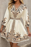 FJØRNA Champagne mini dress with printed V-neck, lantern sleeves, and waist tie, styled for a chic, elegant look.