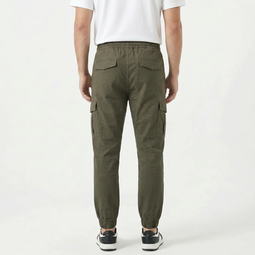 Men's slim fit cotton cargo trousers by FJØRNA, shown in a neutral color with multiple cargo pockets and a tapered leg fit.