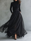 Elegant black tulle maxi dress by FJØRNA featuring flowing fabric, patchwork details, and a fitted knit design.