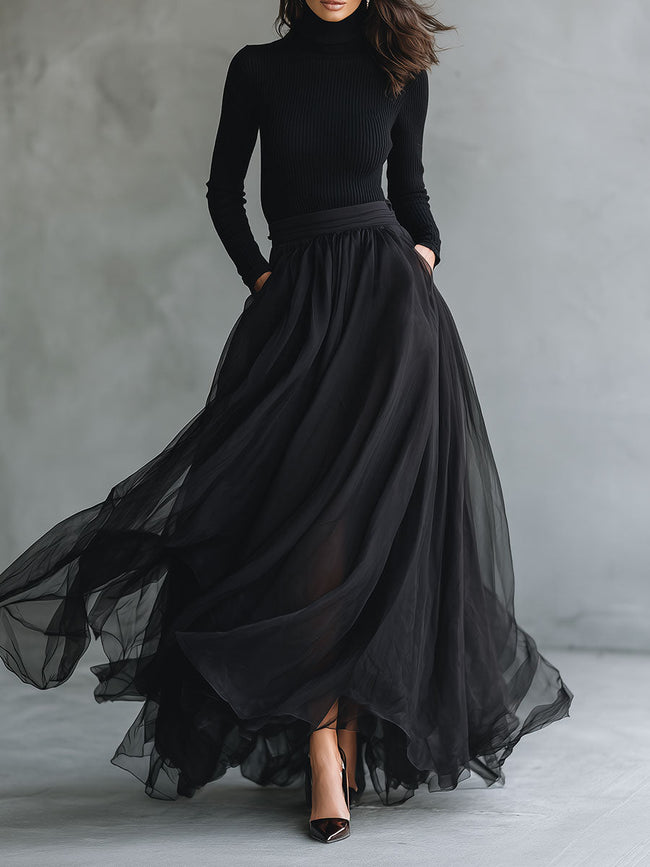 Elegant black tulle maxi dress by FJØRNA featuring flowing fabric, patchwork details, and a fitted knit design.