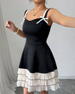 Black pleated mini summer party dress by FJØRNA with white bows, perfect for festive occasions and warm weather events.