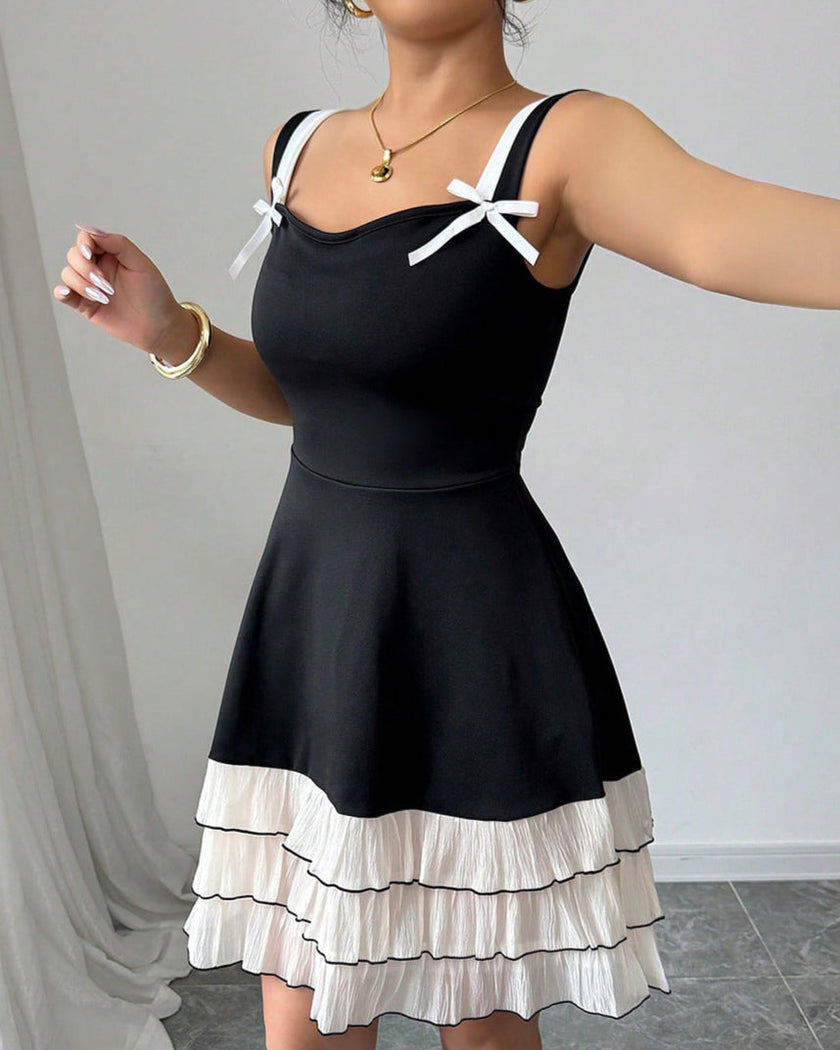 Black pleated mini summer party dress by FJØRNA with white bows, perfect for festive occasions and warm weather events.