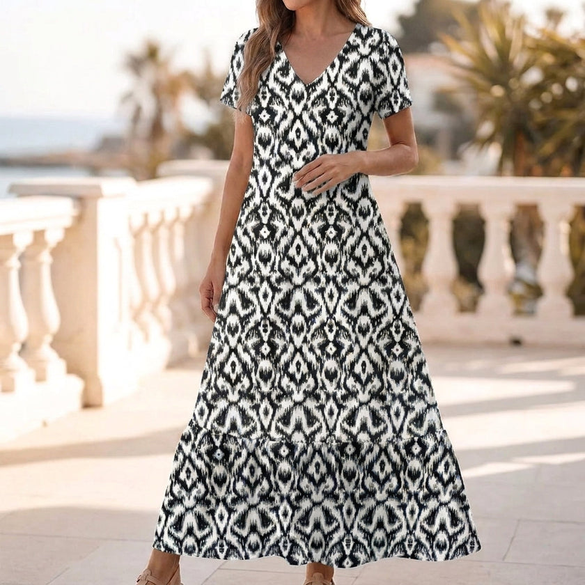 Black FJØRNA ruffled hem A-line maxi dress for women, featuring a flowing silhouette and elegant design.