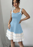 FJØRNA summer party dress featuring blue color, bow detail, and ruffle accents, front view of a stylish mini dress.