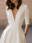 FJØRNA elegant deep V-neck pleated A-line midi dress displayed on a model, showcasing its sophisticated design and flowing fabric.