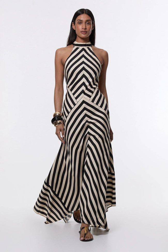 FJØRNA Mono Fluid Stripe Maxi Halter Dress in white, flowing fabric, sleeveless design, and elegant halter neckline.