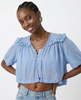 FJØRNA women's cotton blouse with ruffle detail, featuring a stylish and breathable top for a feminine look.