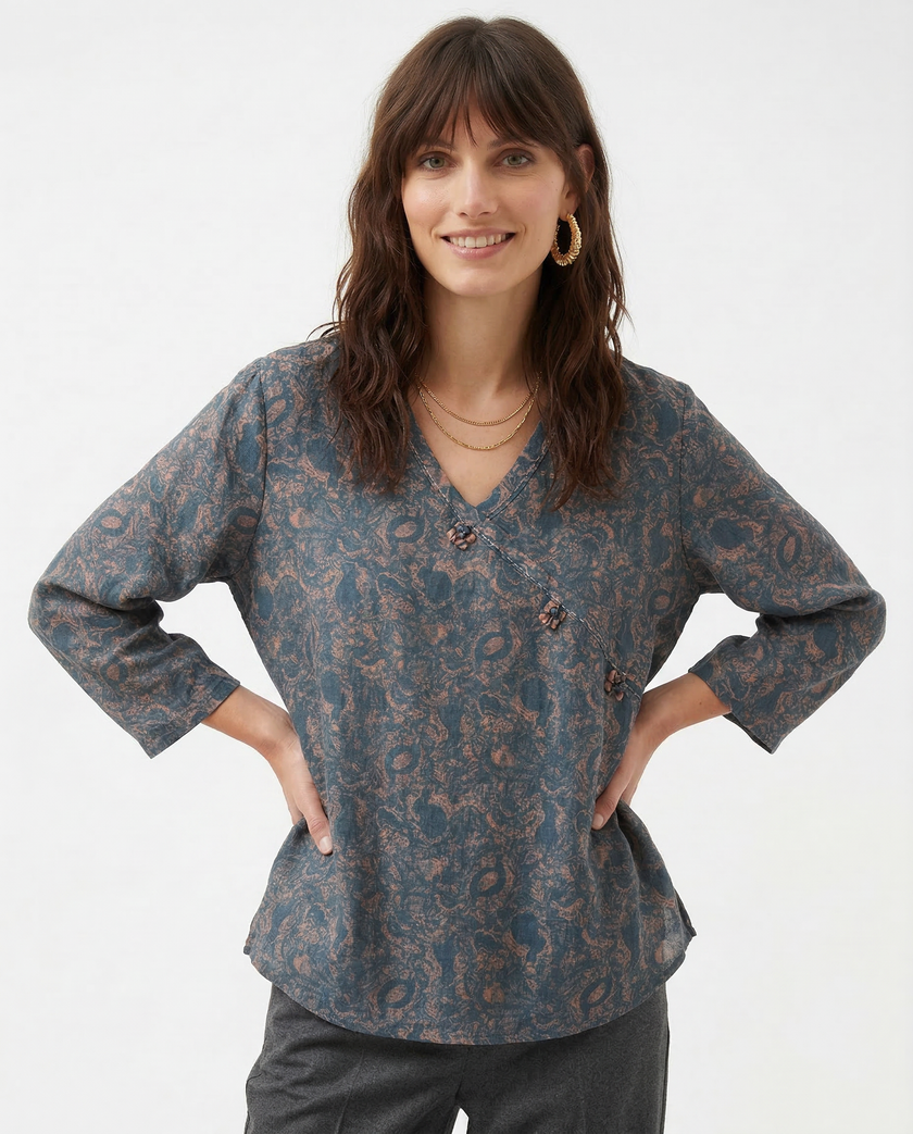 FJØRNA Kaien wrap-style blouse in lightweight fabric, featuring a fitted waist and long sleeves, displayed on a neutral background.