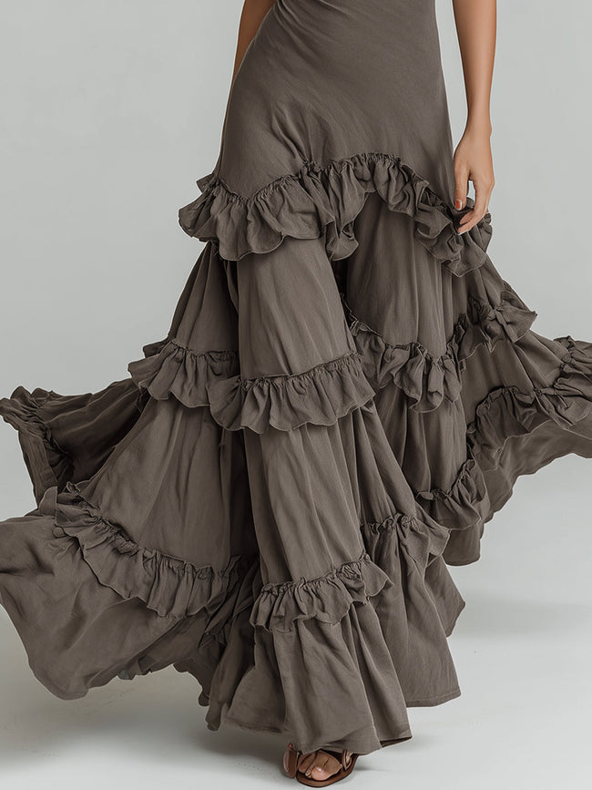 Bohemian style halter neck ruffled maxi dress by FJØRNA displayed on a hanger with flowing fabric and intricate ruffle details.