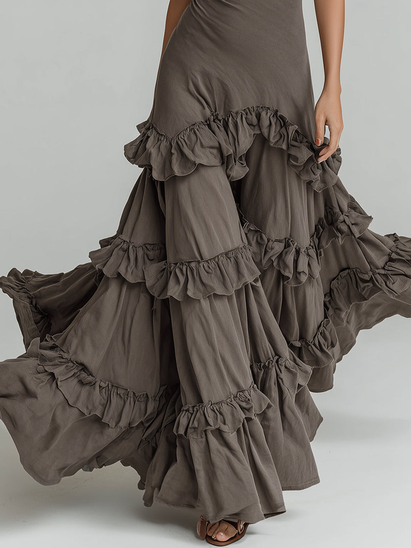 Bohemian style halter neck ruffled maxi dress by FJØRNA displayed on a hanger with flowing fabric and intricate ruffle details.