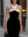 FJØRNA black velvet midi dress featuring a white halter neck bow detail and elegant, flowing design.