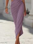 Lavender purple ruched midi dress by FJØRNA displayed on a hanger, showcasing the fitted bodice and flowing skirt.